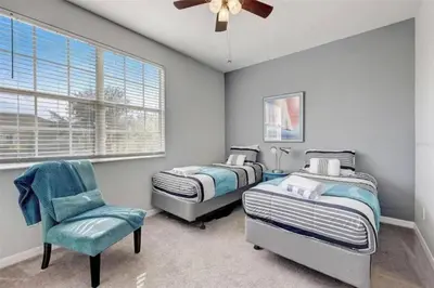 a bedroom with two beds and a chair and a ceiling fan at Five Vacation Homes - Orlando in Orlando