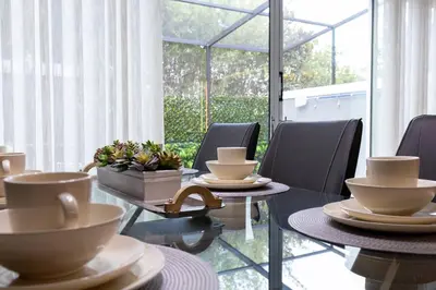 a dining room with chairs and tables with cups on them at Beautiful Townhome with Splash Pool near Disney 31 in Kissimmee