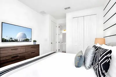 a white bedroom with a large bed and a flat screen tv at Upstay-Mansion w Spa-Pool-Cinema-Games - Sleeps 36 in Kissimmee