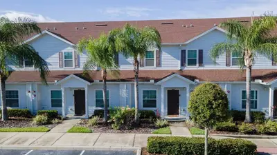 a white house with palm trees in front of it at Family Spacious 3BR Townhouse with BBQ n' Pool Access in Kissimmee