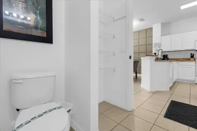 a white bathroom with a toilet and a kitchen at 3 Bed 2,5 Bath Perfect Family home Bunk Beds townhouse in Kissimmee