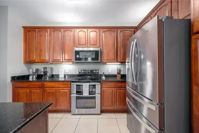 a kitchen with wooden cabinets and a stainless steel refrigerator at Vista Cay Luxury Rhapsody condo in Orlando