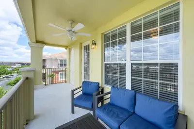 a balcony with two blue chairs and a ceiling fan at Stunning Vacation Condo - Vista Cay Resort - 2016 in Orlando