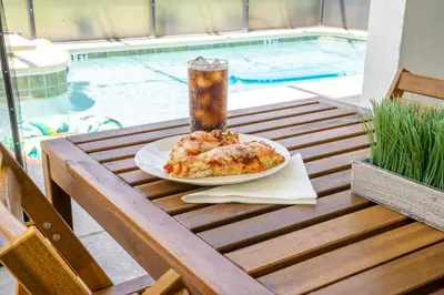 a plate of pizza on a table next to a pool at Storey Lake Pool Home with Resort Amenities near DISNEY in Kissimmee