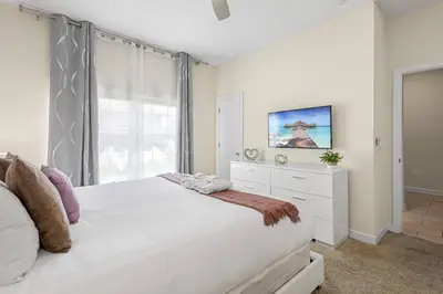 a white bedroom with a large bed and a window at 4978 Luxurious 4BR Sunshine Getaway at Storey Lake in Kissimmee