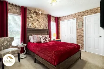 a bedroom with a red bed and a chair at Amazing 6bd Resort Home Pool & Near Disney in Kissimmee