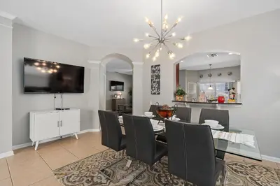 a dining room with a table and chairs and a television at Modern Luxury 6 Bed Pool Home Close To Disney in Orlando