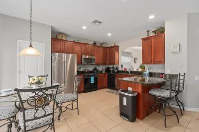 a kitchen with wooden cabinets and a table and chairs at Modern Luxury 6 Bed Pool Home Close To Disney in Orlando