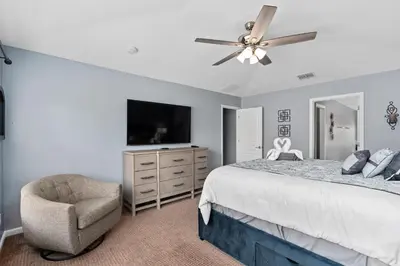 a bedroom with a bed and a tv and a chair at Modern Luxury 6 Bed Pool Home Close To Disney in Orlando