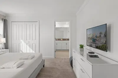 a white bedroom with a bed and a tv on the wall at Modern design near Disney Top resort in Kissimmee