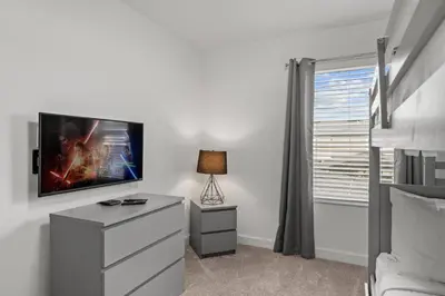 a bedroom with a dresser and a tv on a wall at Modern design near Disney Top resort in Kissimmee
