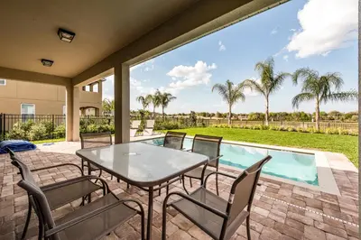 a patio with a table and chairs next to a swimming pool at Lovely Home With Theme Rooms, Game Room With Waterpark & Resort Access Resort Access At Encore Resort- 7705By in Kissimmee