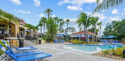 a resort pool with blue chairs and palm trees at 201 HB - Hideaway at TerraVerde in Kissimmee