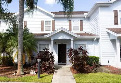 a white house with palm trees in front of it at 3 Bedroom 2 Bathroom Lucaya Village 15-103 in Kissimmee