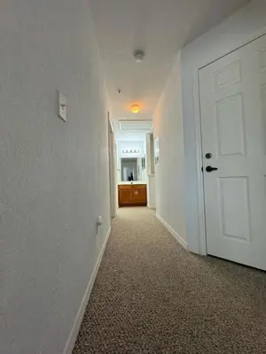 an empty hallway with a white door and a kitchen at 4 Bedroom 3 Bathroom Villas At Seven Dwarfs 10-102 in Kissimmee