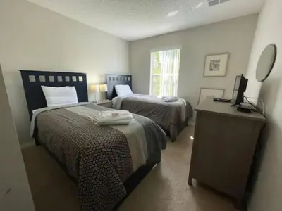 a bedroom with two beds and a dresser and a mirror at 3 Bedroom 3 Bathroom Terra Verde 4766 in Kissimmee