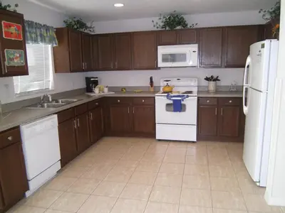 a kitchen with wooden cabinets and white appliances at 4 Bedroom Value Plus Home with Private PooI in Orlando