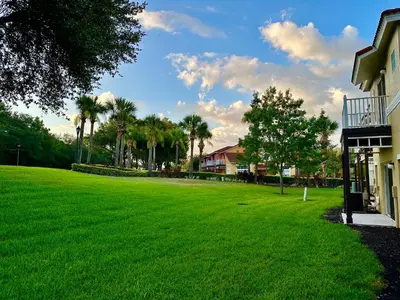 a large green yard next to a house with palm trees at Grand Emerald 3BR Condo Resort near Disney Parks in Kissimmee