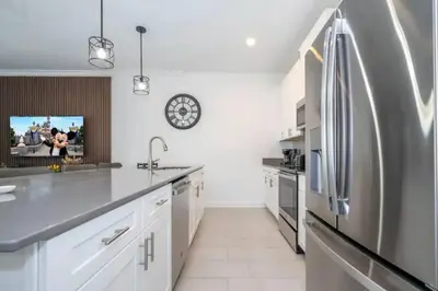 a kitchen with white cabinets and a stainless steel refrigerator at Condominium villas near Disney Orlando Florida in Kissimmee