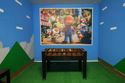 a ping pong table in a room with a poster on the wall at Themed 5BD Home Movie and Game Room 4726 in Kissimmee