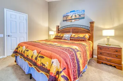 a bedroom with a large bed and a dresser with a lamp at Magical Getaway Close to Disney! Pool, Gym, & WiFi in Kissimmee