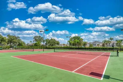 a tennis court with two tennis courts at Magical Getaway Close to Disney! Pool, Gym, & WiFi in Kissimmee