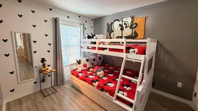a childs bedroom with a bunk bed with mickey mouse sheets at Stay Close to Disney in Your 3-Bedroom Haven in Kissimmee