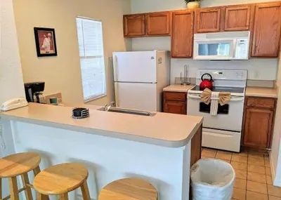 a kitchen with a white refrigerator and wooden cabinets at 4 Bedroom 3 Bathroom Villas At Seven Dwarfs 17-107 in Kissimmee