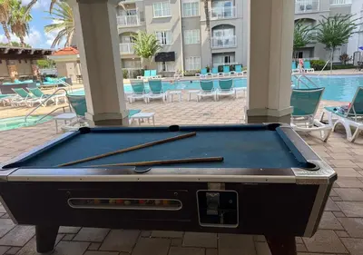 a pool table sitting on a patio next to a swimming pool at The Point Hotel Apartment 603 Near to Universal in Orlando