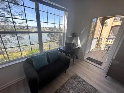 a living room with a couch and a desk and large windows at WH7660-205CS - Lakeview on the hills in Orlando
