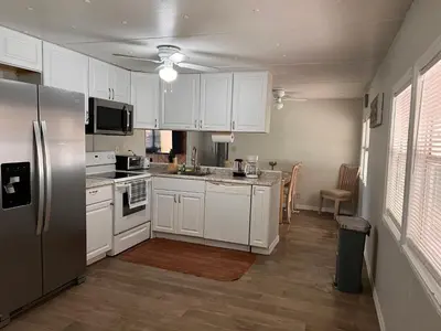 a kitchen with white cabinets and a stainless steel refrigerator at Mobile Home on huge parking space 10 mins from airport, 20 mins from Disney in Kissimmee