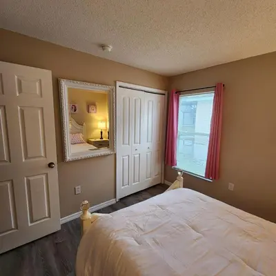 a bedroom with a bed and a mirror and a window at 4 Bedroom villa in Lake Berkley, Private Pool Fantastic View, Free WiFi, Theme Parks All Around! in Kissimmee