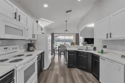 a white kitchen with white appliances and a table at 637- Huge 5 Bed Villa with Amazing Water Views and Own Private Pool and Spa in Kissimmee