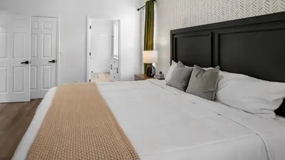 a large white bed with a black headboard in a bedroom at Beautiful 7 Bed Family Pool Home with Game Room-8510PHD in Kissimmee
