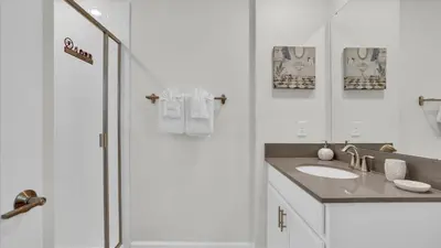 a white bathroom with a sink and a shower at Canoe Landing in Orlando