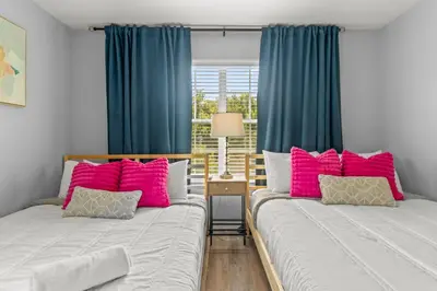 two beds in a room with blue curtains and pink pillows at Lake view Pool home near Disney - 5BR 4BA in Kissimmee