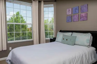 a bedroom with a white bed with two windows at Cozy Apartment 3BD2BA at Windsor Hills WH28131 in Orlando