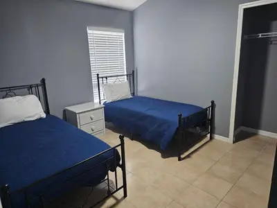 a bedroom with two beds with blue sheets and a window at Mufasa's Pride in Kissimmee