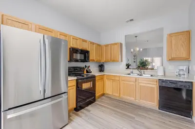 a kitchen with a stainless steel refrigerator and wooden cabinets at Camaro in Orlando