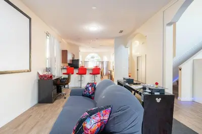 a living room with a blue couch and a kitchen at Amazing Star Wars & Disney Vr Gaming House! in Kissimmee