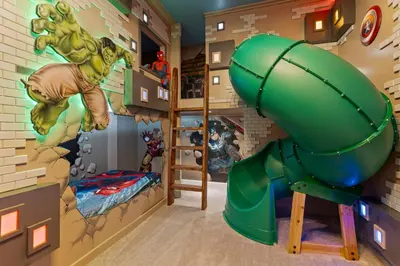 a childrens room with a superhero mural and a green slide at Brand NEW 12Bed12Bath At Paradiso Grande in Orlando
