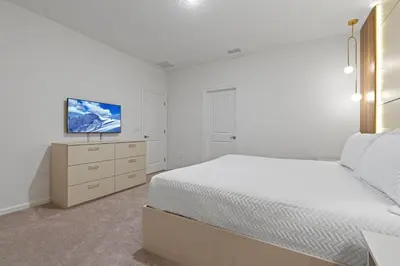 a white bedroom with a bed and a tv at Brand NEW 12Bed12Bath At Paradiso Grande in Orlando