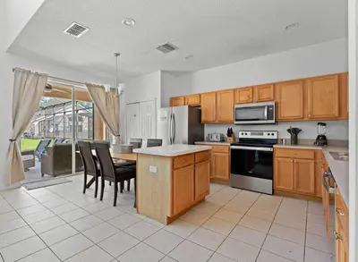 a kitchen with wooden cabinets and a table and chairs at 7BR Family Friendly Resort Pool Home Near Disney World in Kissimmee