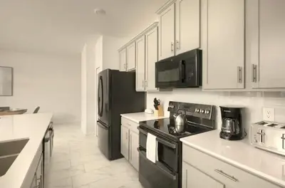 a kitchen with black appliances and white cabinets at Your 4-Bedroom Getaway, Only 9 Miles from Disney in Kissimmee