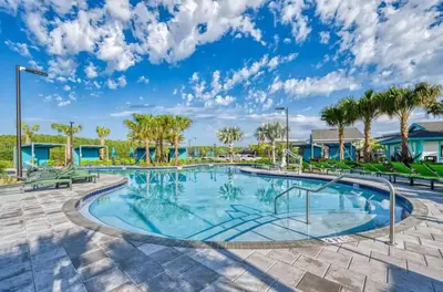 a large swimming pool with palm trees in a resort at Your 4-Bedroom Getaway, Only 9 Miles from Disney in Kissimmee