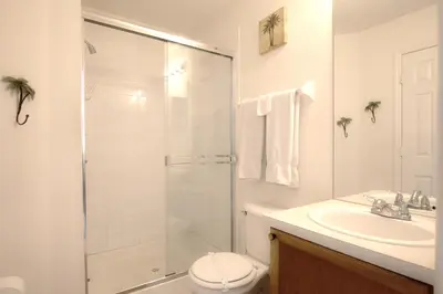 a white bathroom with a shower and a sink at Windsor Palm Resort 3 miles to Disney 4 Bedrooms in Kissimmee