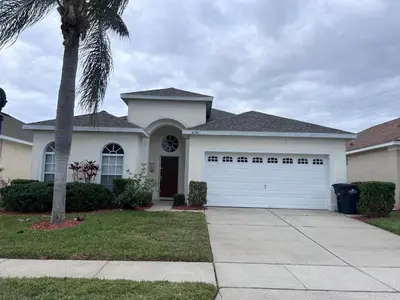a house with a white garage door and a palm tree at Windsor Palm Resort 3 miles to Disney 4 Bedrooms in Kissimmee