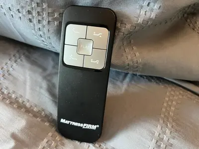 a remote control sitting on top of a pillow at DisneyShuttleKing & Queen Be 5 minutes to Disney in Orlando