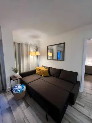 a living room with a black couch and a mirror at Renovated and cozy apartment near universal in Orlando