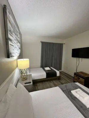 a hotel room with two beds and a television at Renovated and cozy apartment near universal in Orlando